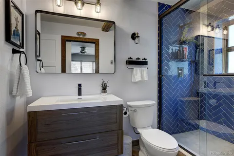 a bathroom with a toilet a sink a mirror a vanity and shower