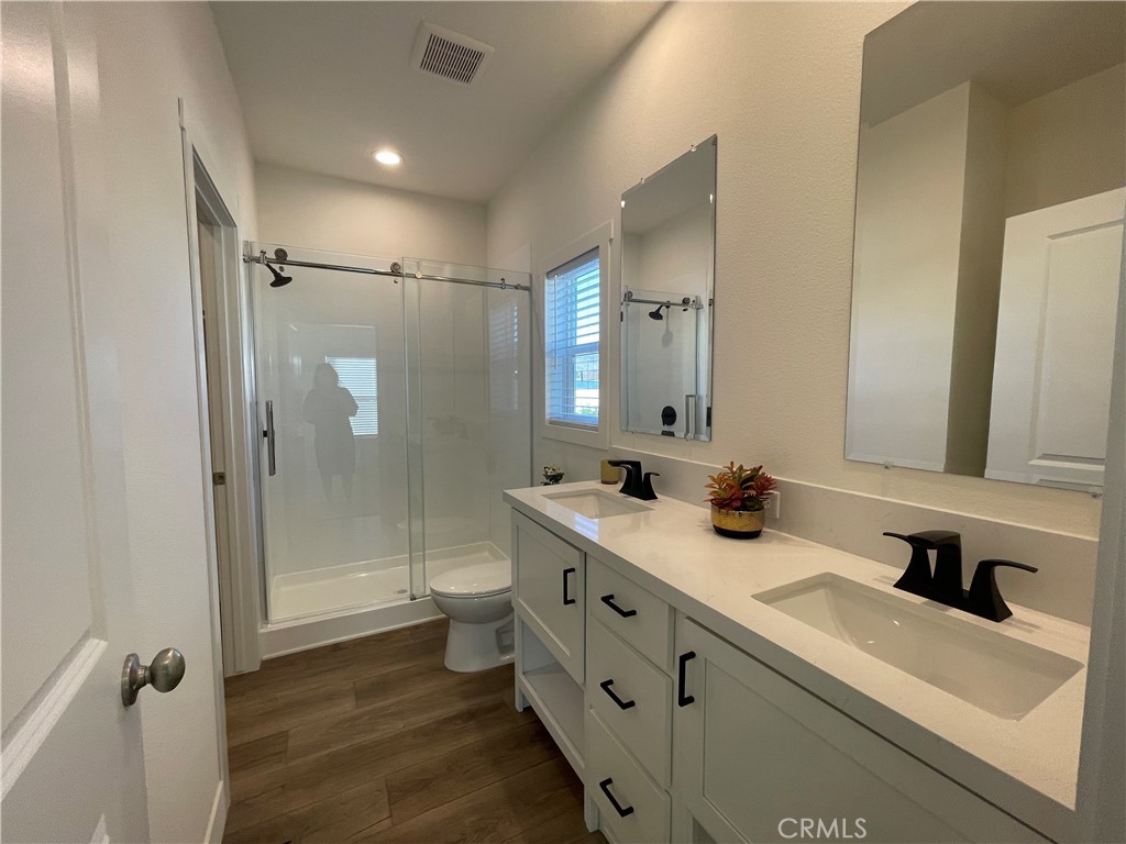 12995 6th Street, Unit 9 Yucaipa, CA 92399 - Photo 30 of 32 a bathroom with a double vanity sink toilet mirror and shower