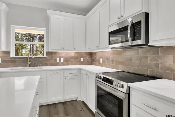 a kitchen with granite countertop white cabinets stainless steel appliances and sink