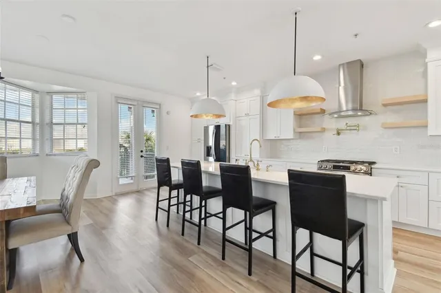 a kitchen with stainless steel appliances granite countertop a kitchen island a table and chairs with wooden floor