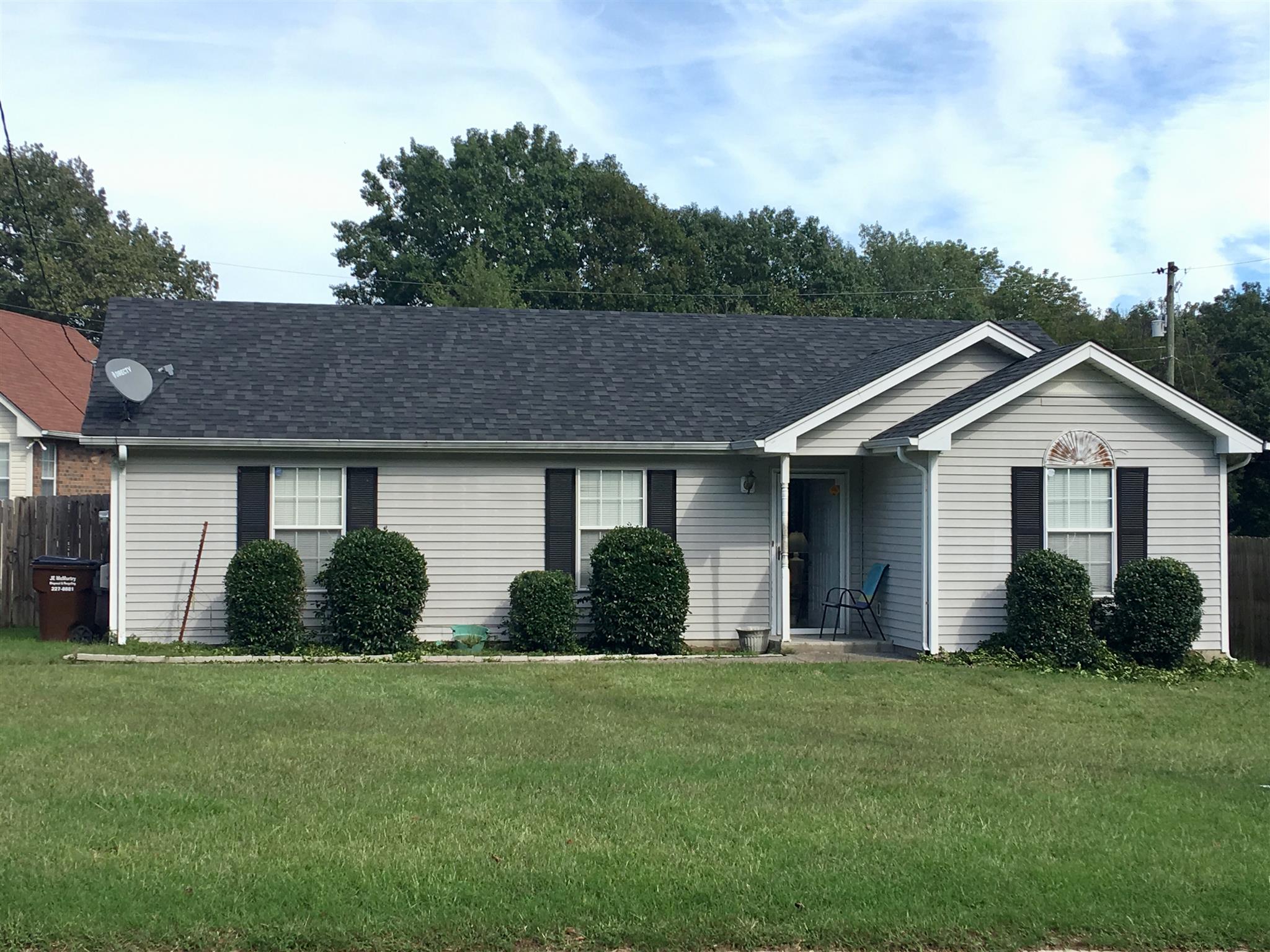 a front view of house with yard and trees in the background