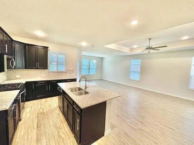 a kitchen with kitchen island granite countertop a sink and cabinets