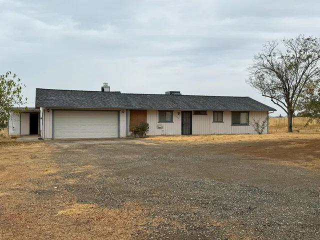 a front view of a house with a garden and trees