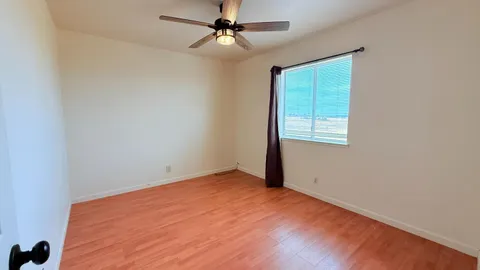 an empty room with a window and ceiling fan