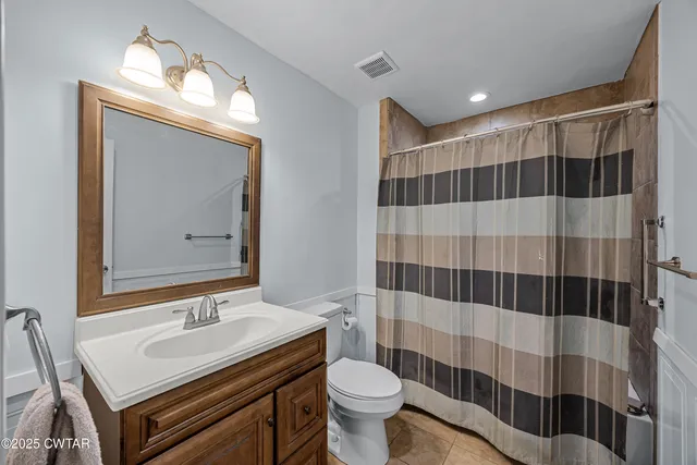 a bathroom with a sink a toilet a mirror and shower curtain