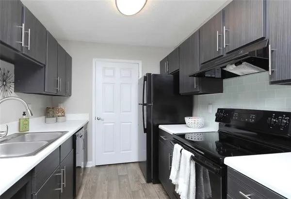 a kitchen with stainless steel appliances granite countertop a sink stove refrigerator and cabinets