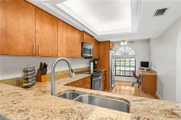 a kitchen with stainless steel appliances kitchen island granite countertop a sink dishwasher and wooden cabinets with a granite countertops