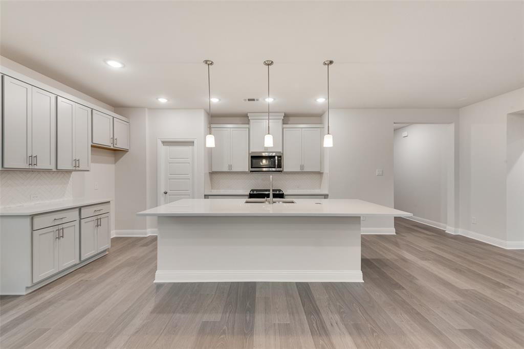 1013 Canoe Way Crowley, TX 76036 - Photo 2 of 26 a large kitchen with granite countertop a large counter top a sink stainless steel appliances and cabinets