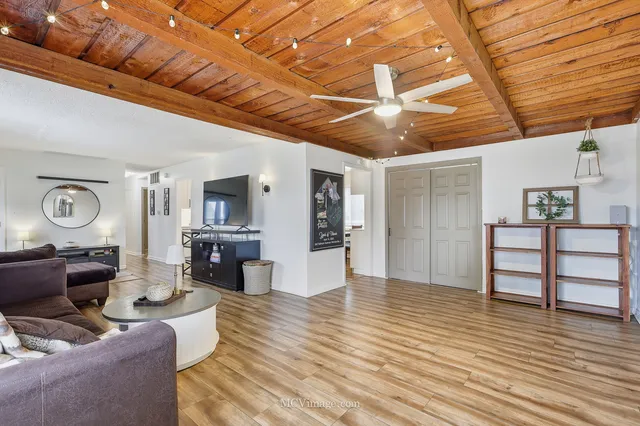 a living room with furniture a large window and wooden floor