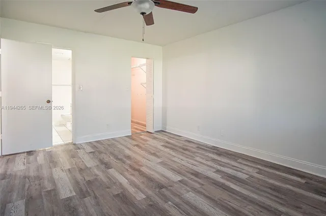 an empty room with wooden floor closet and windows