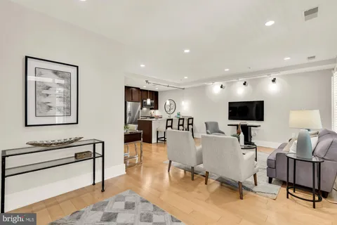 a living room with furniture and a flat screen tv with kitchen view
