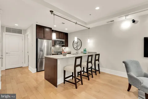 a kitchen with stainless steel appliances granite countertop a dining table chairs refrigerator and microwave