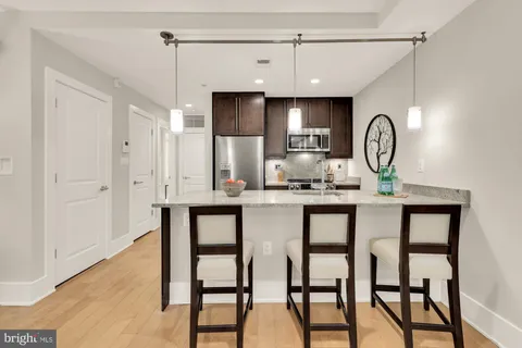 a kitchen with granite countertop a table chairs refrigerator and microwave