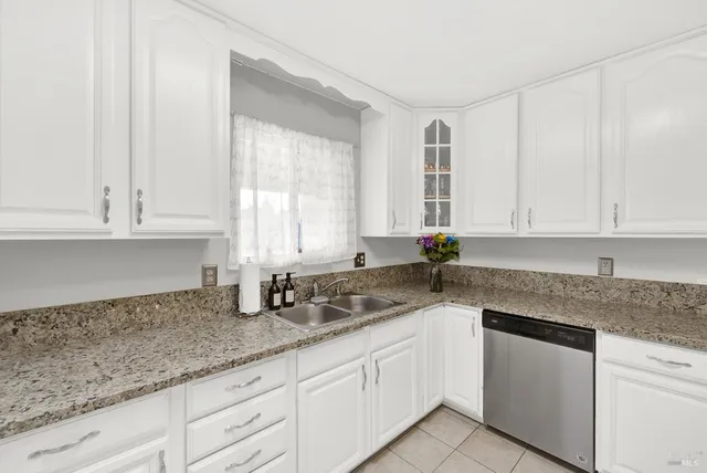 a kitchen with granite countertop white cabinets white appliances and a sink