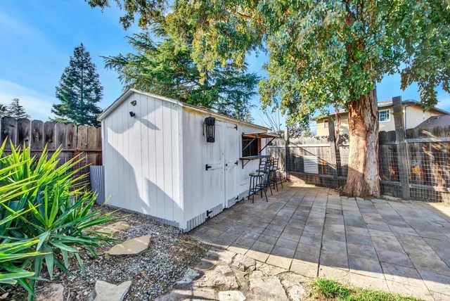 a view of a white house with a small yard and large tree