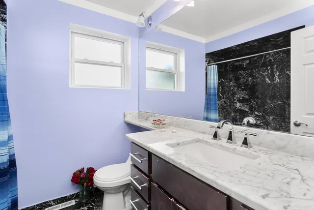 a bathroom with a granite countertop sink a toilet and a mirror