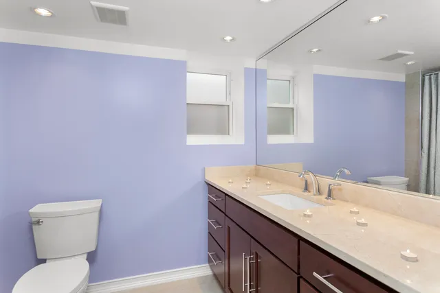 a bathroom with a granite countertop sink a toilet and a mirror