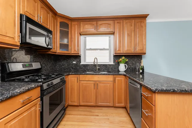 a kitchen with granite countertop stainless steel appliances a stove a sink a microwave and cabinets