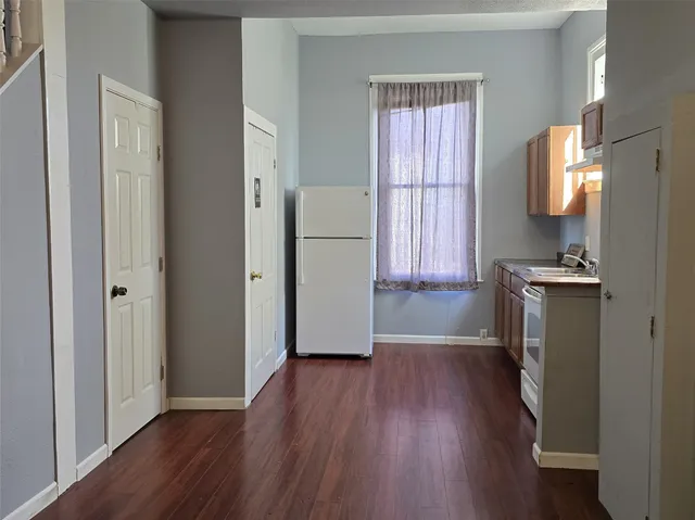 a view of a kitchen with a fridge wooden floor and a window