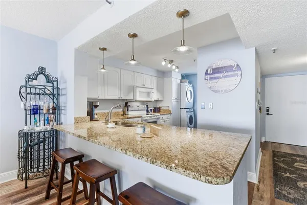a kitchen with kitchen island granite countertop a sink a counter top space and living room view