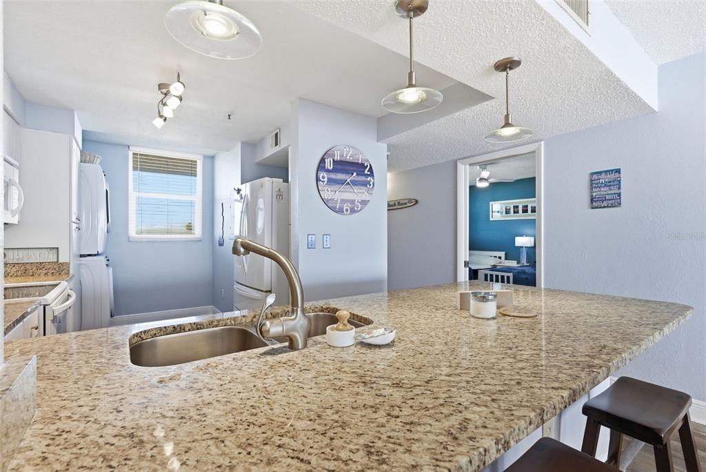 15462 Gulf Boulevard, Unit 406 Madeira Beach, FL 33708 - Photo 19 of 48 a kitchen with kitchen island granite countertop a sink a counter top space and living room view