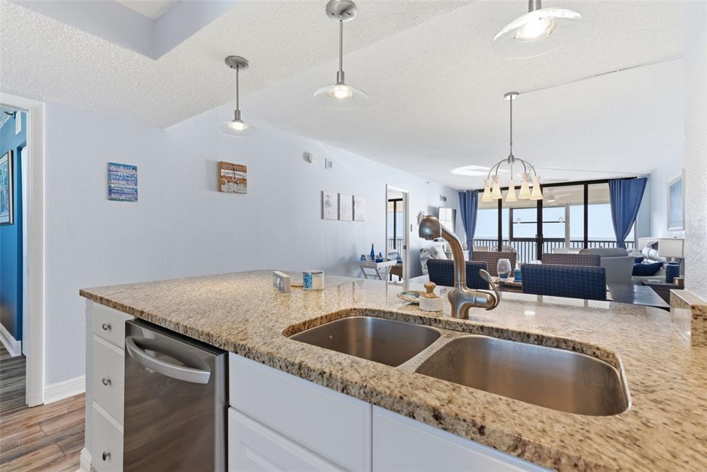 15462 Gulf Boulevard, Unit 406 Madeira Beach, FL 33708 - Photo 23 of 48 a kitchen with granite countertop a sink a counter top space and living room view