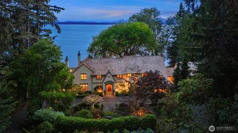 a view of a lake with lawn chairs and large trees