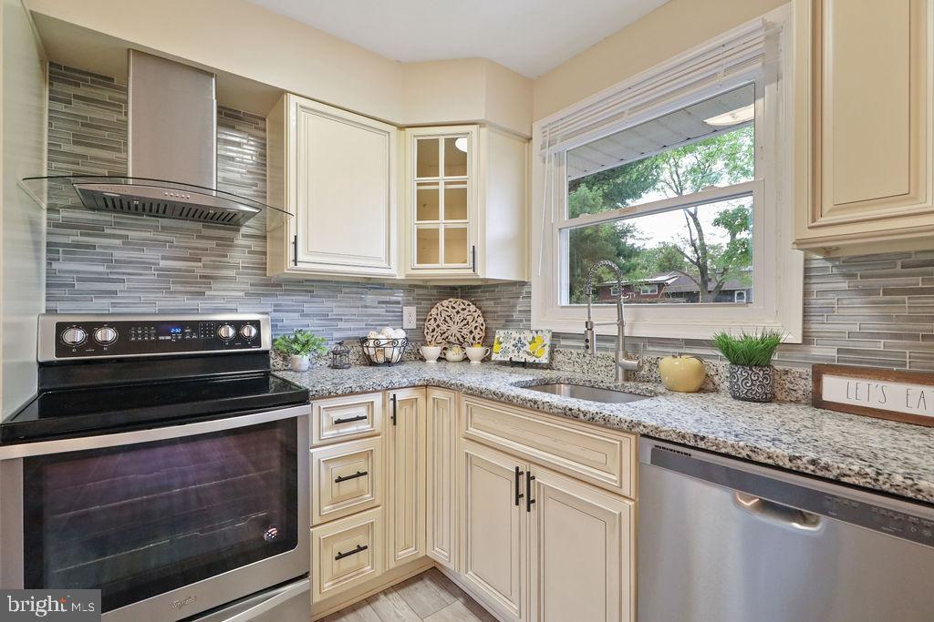a kitchen with granite countertop stainless steel appliances white cabinets and a window
