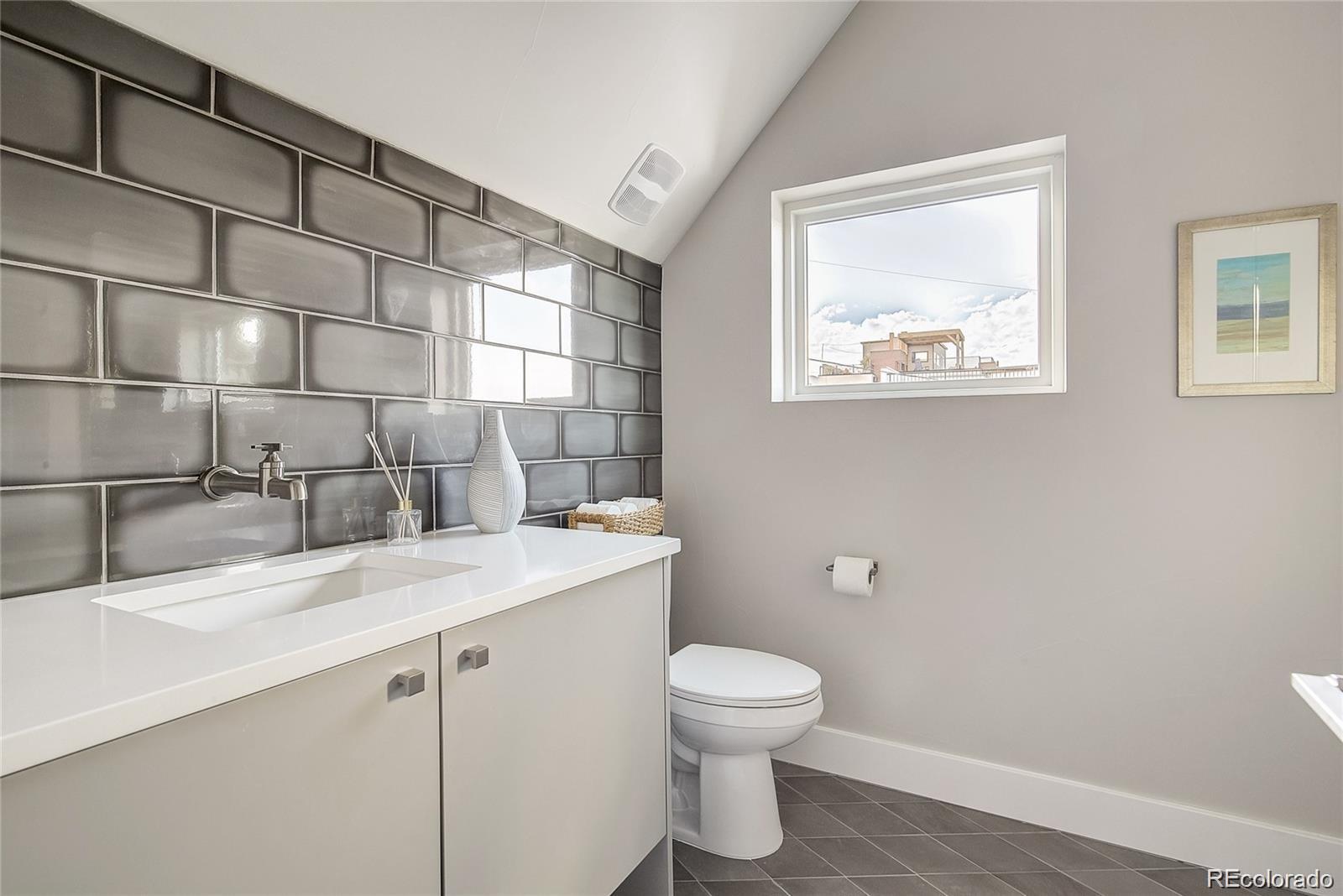 1811 West 32nd Avenue, Unit R Denver, CO 80211 - Photo 21 of 40 a bathroom with a granite countertop sink toilet and a mirror