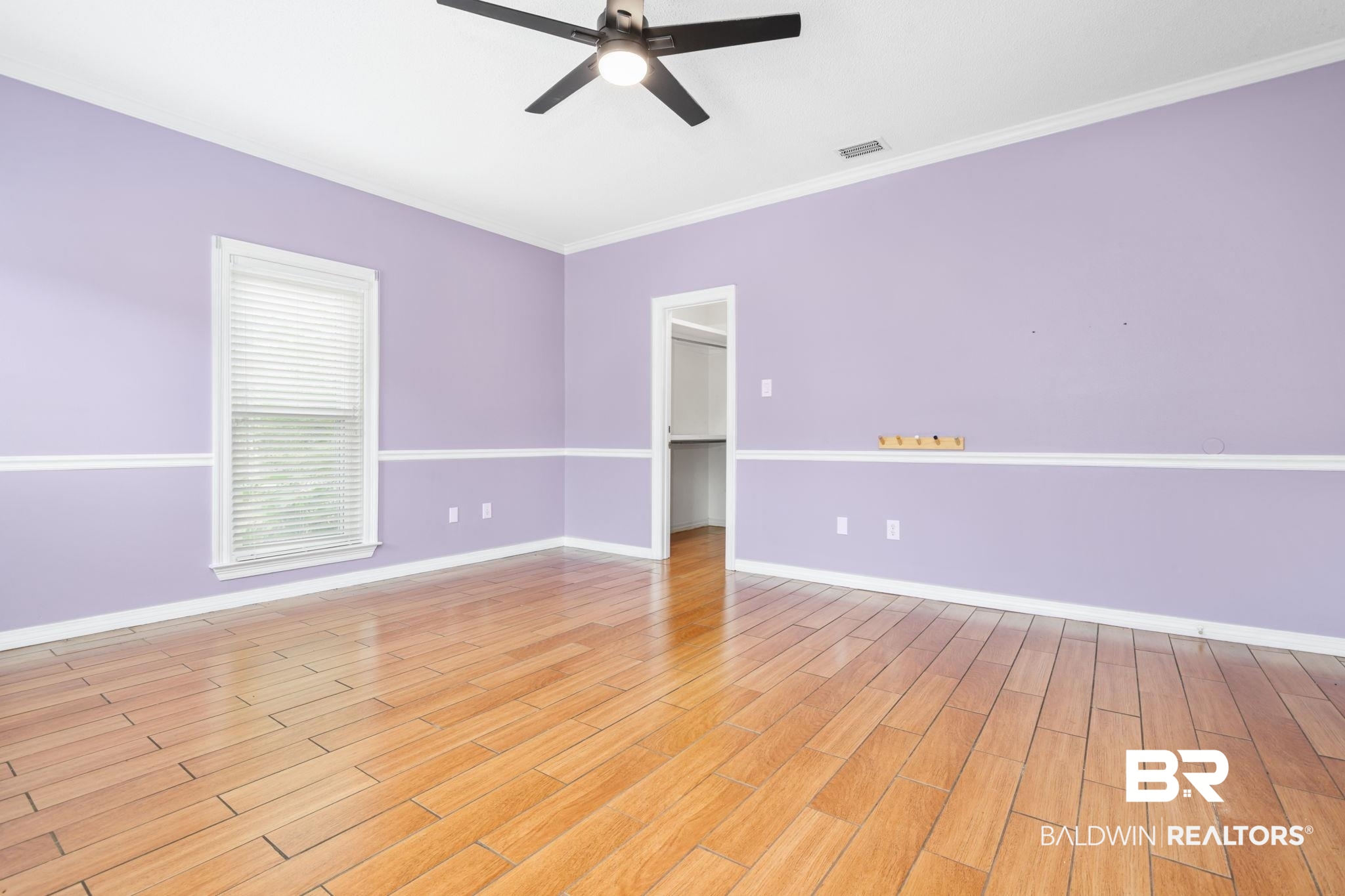 7540 2 Mile Road Irvington, AL 36544 - Photo 53 of 82 Room featuring wood-finish flooring, a ceiling fan with integrated lighting, window with blinds, and white crown molding and chair rail accents