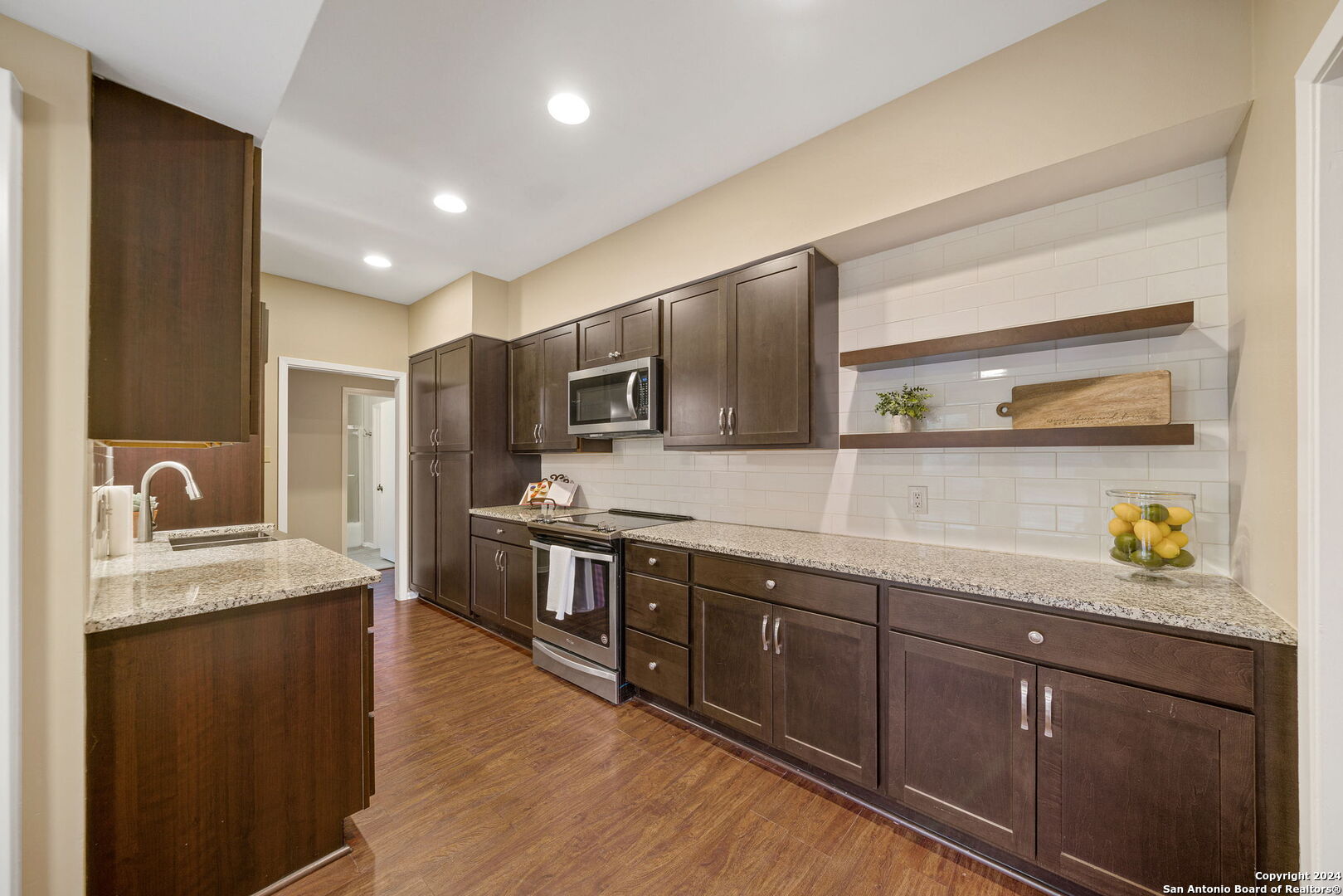 a large kitchen with stainless steel appliances granite countertop a sink counter space and wooden floor