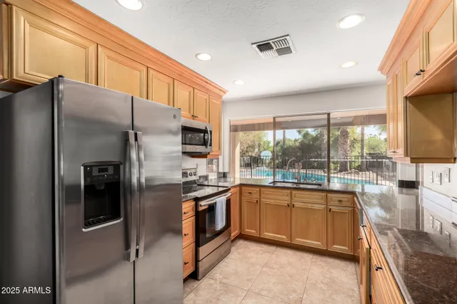 a kitchen with stainless steel appliances granite countertop a refrigerator a stove and a sink with cabinets