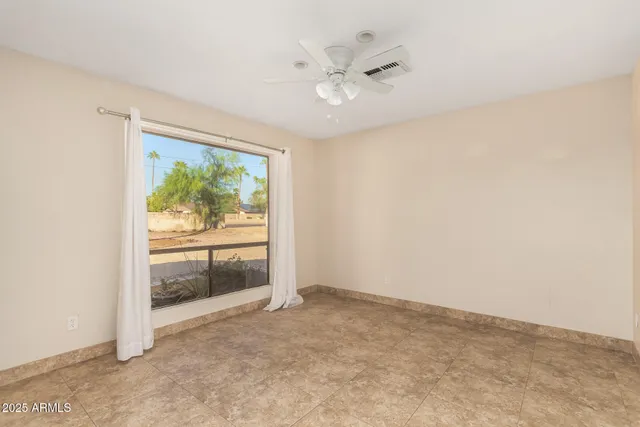 an empty room with a ceiling fan and carpet