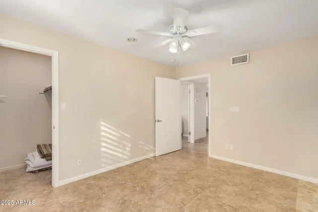 an empty room with chandelier fan and windows