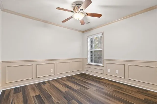 a view of an empty room with chandelier fan and wooden floor