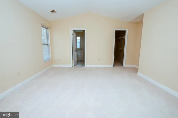 a view of an empty room with closet and a window