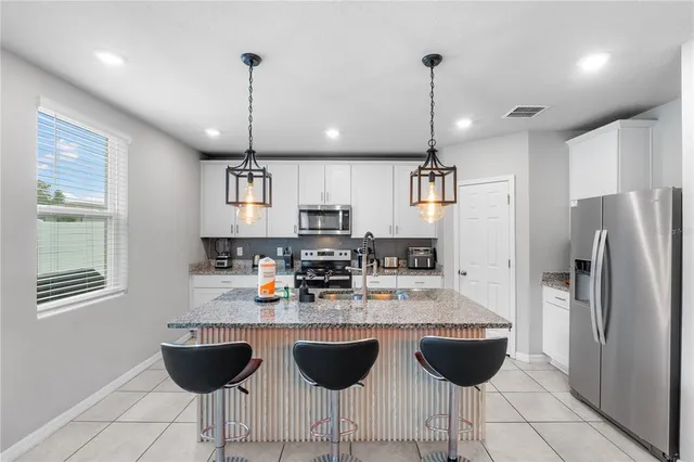 a kitchen with stainless steel appliances granite countertop a refrigerator a stove a sink and a microwave