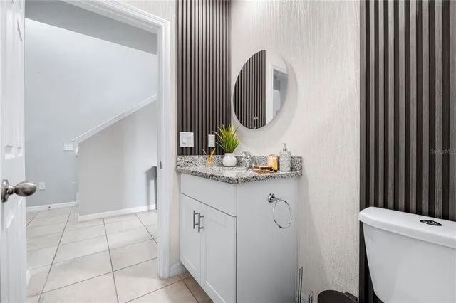 a bathroom with a granite countertop sink a toilet and a mirror