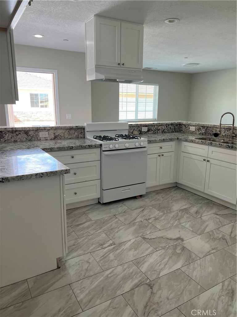 16550 Olive Street Hesperia, CA 92345 - Photo 3 of 9 a kitchen with granite countertop a sink stove and cabinets