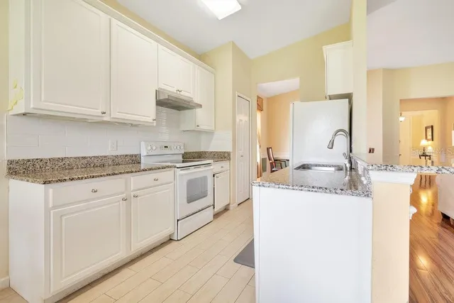 a kitchen with granite countertop a sink and white cabinets
