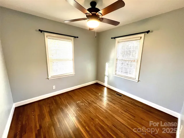 a view of an empty room with window and wooden floor