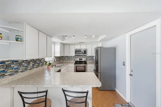 a kitchen with stainless steel appliances granite countertop a refrigerator a stove and a sink