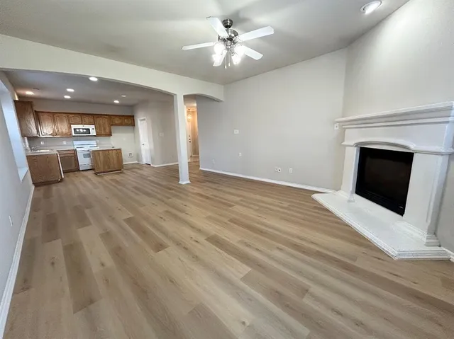 a view of a livingroom with a fireplace a ceiling fan and a kitchen counter top space