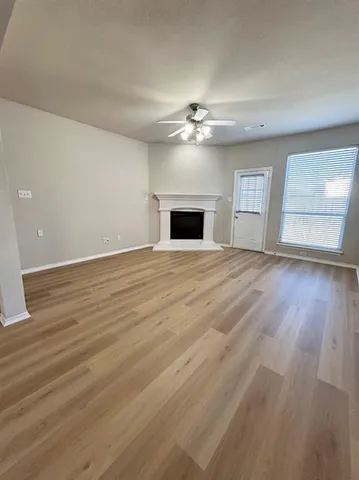 a view of empty room with wooden floor and fireplace