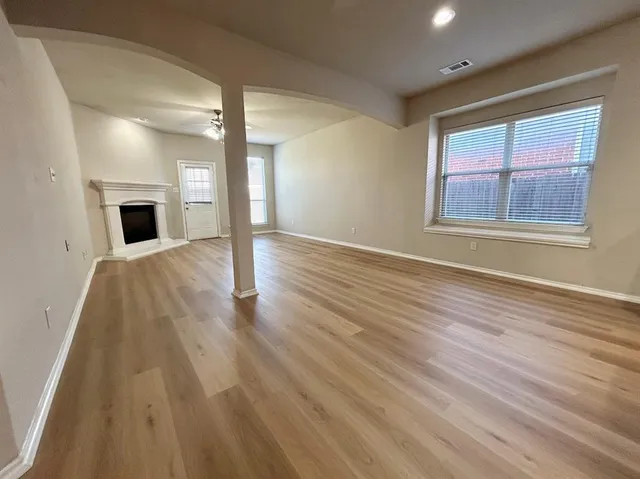 a view of empty room with fireplace and wooden floor
