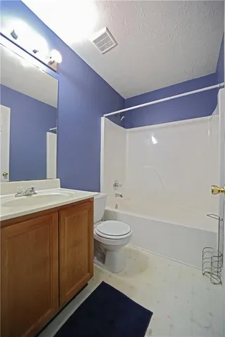 a bathroom with a toilet sink vanity granite and mirror