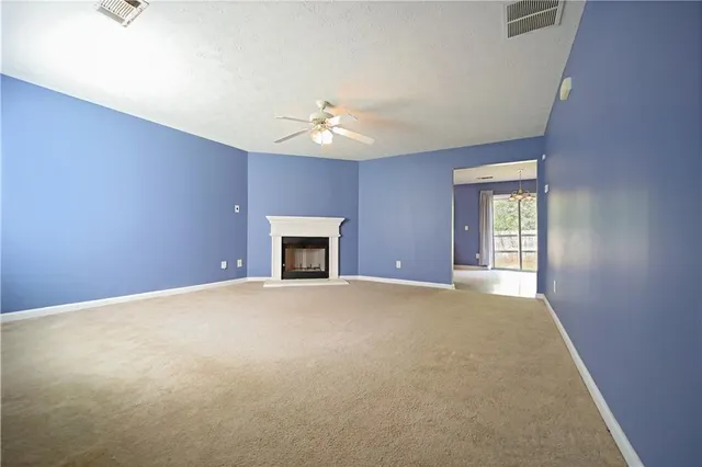 an empty room with chandelier fan and windows