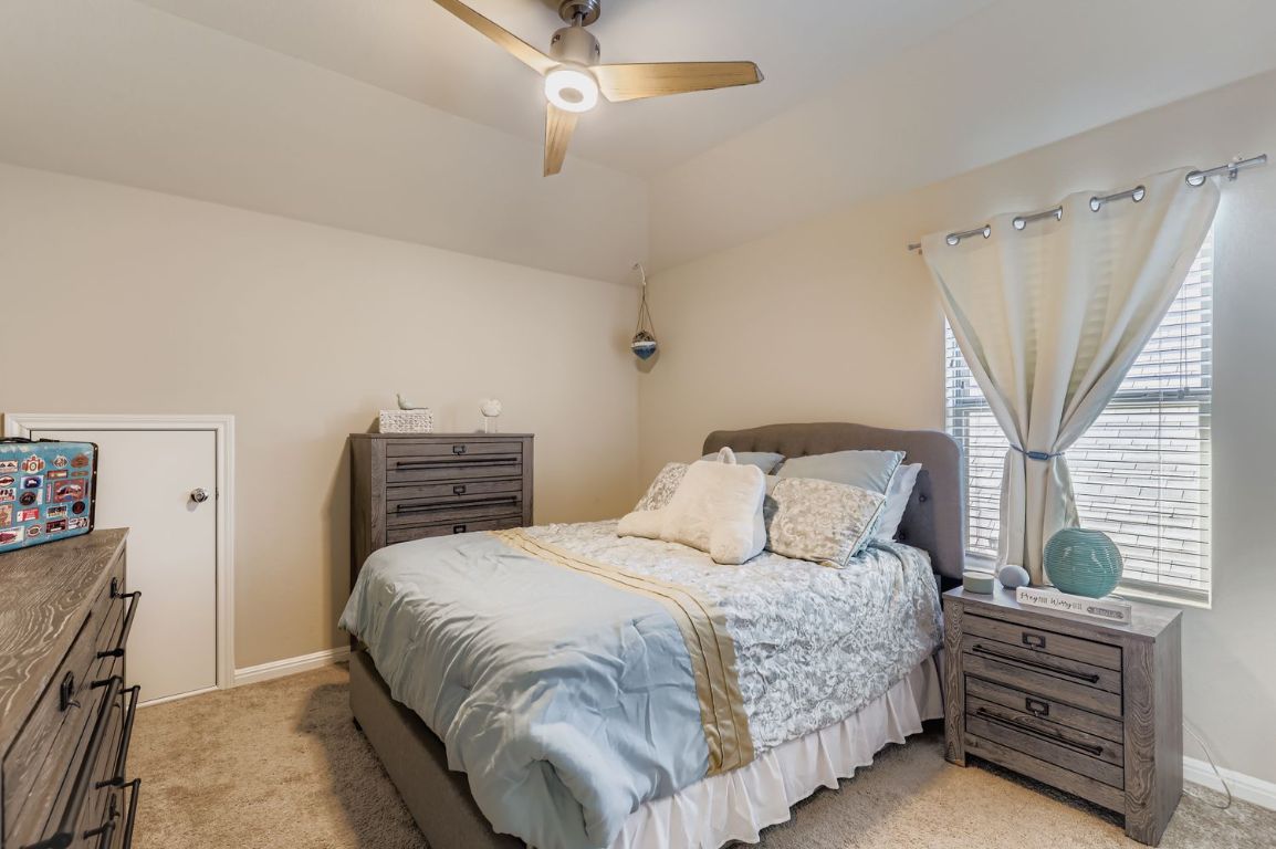 19433 Colgin Drive Pflugerville, TX 78660 - Photo 17 of 29 a bedroom with a bed next to a window with a chandelier