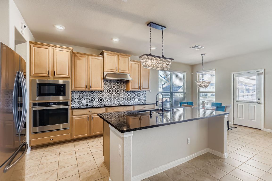 19433 Colgin Drive Pflugerville, TX 78660 - Photo 7 of 29 a kitchen with stainless steel appliances granite countertop a sink a stove and refrigerator