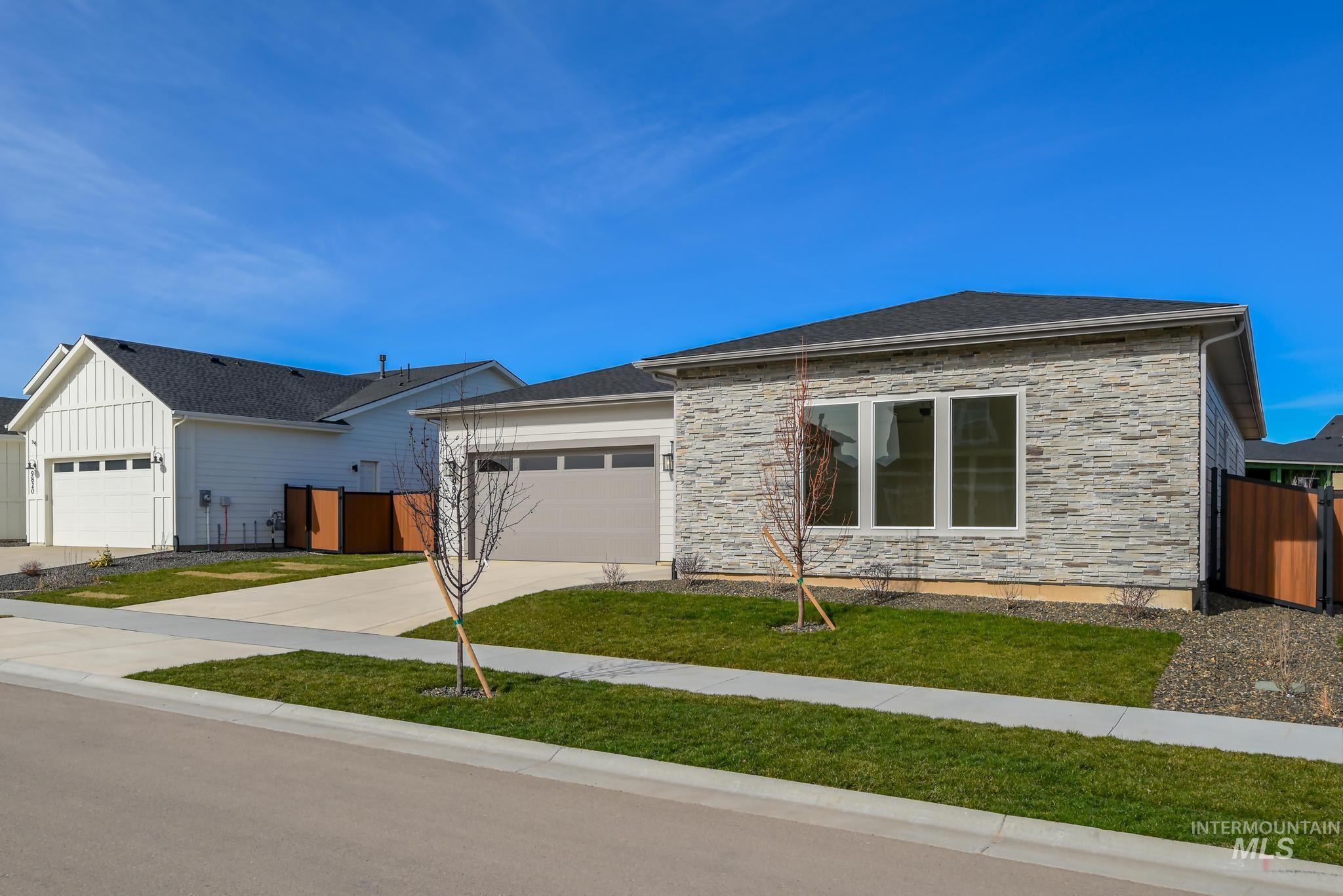 9800 West Novato Street Star, ID 83669 - Photo 3 of 40 View of front of property with stone siding, an attached garage, driveway, and a gate
